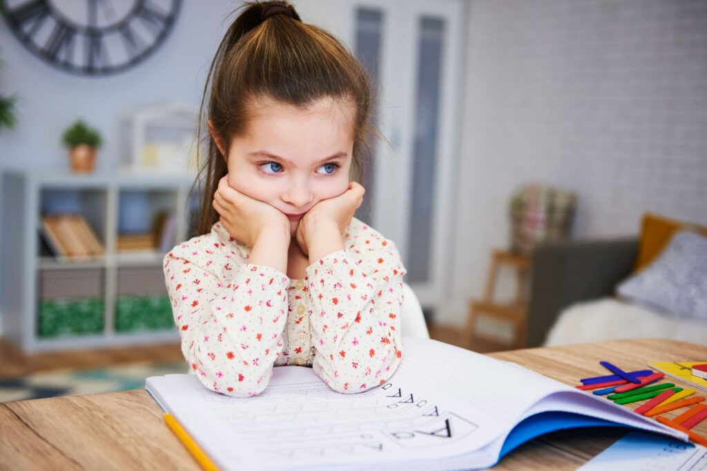 Petite fille peu concentrée devant ses devoirs et leçons