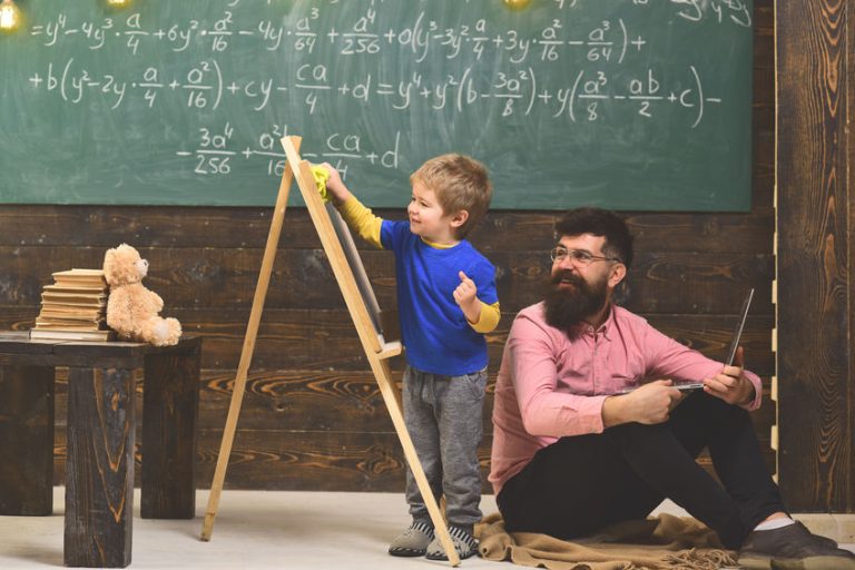 Papa qui aide son enfant à faire ses devoirs dans le plaisir avec un tableau et une peluche