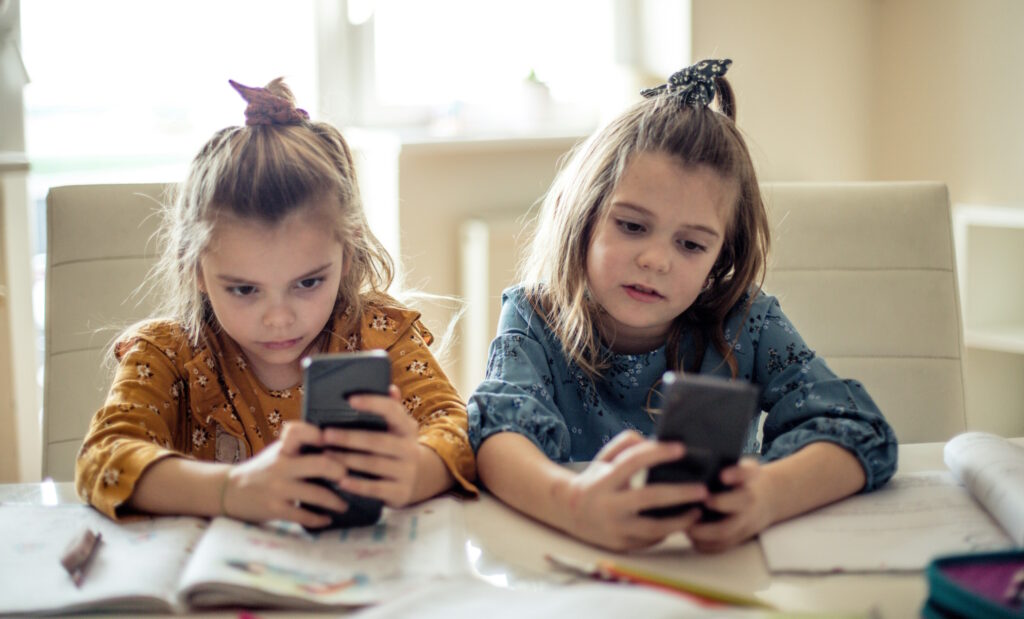 Deux jeunes filles sont déconcentrées par leur écran de téléphone durant leurs devoirs